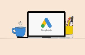 "Illustration of a laptop displaying the Google Ads logo, with a coffee cup and a pen holder beside it." Caption: